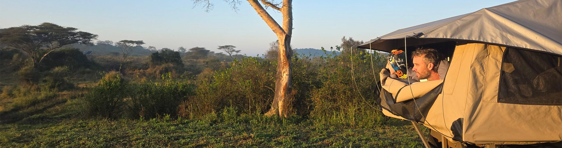 Father and son peaking out of tent in African landscape
